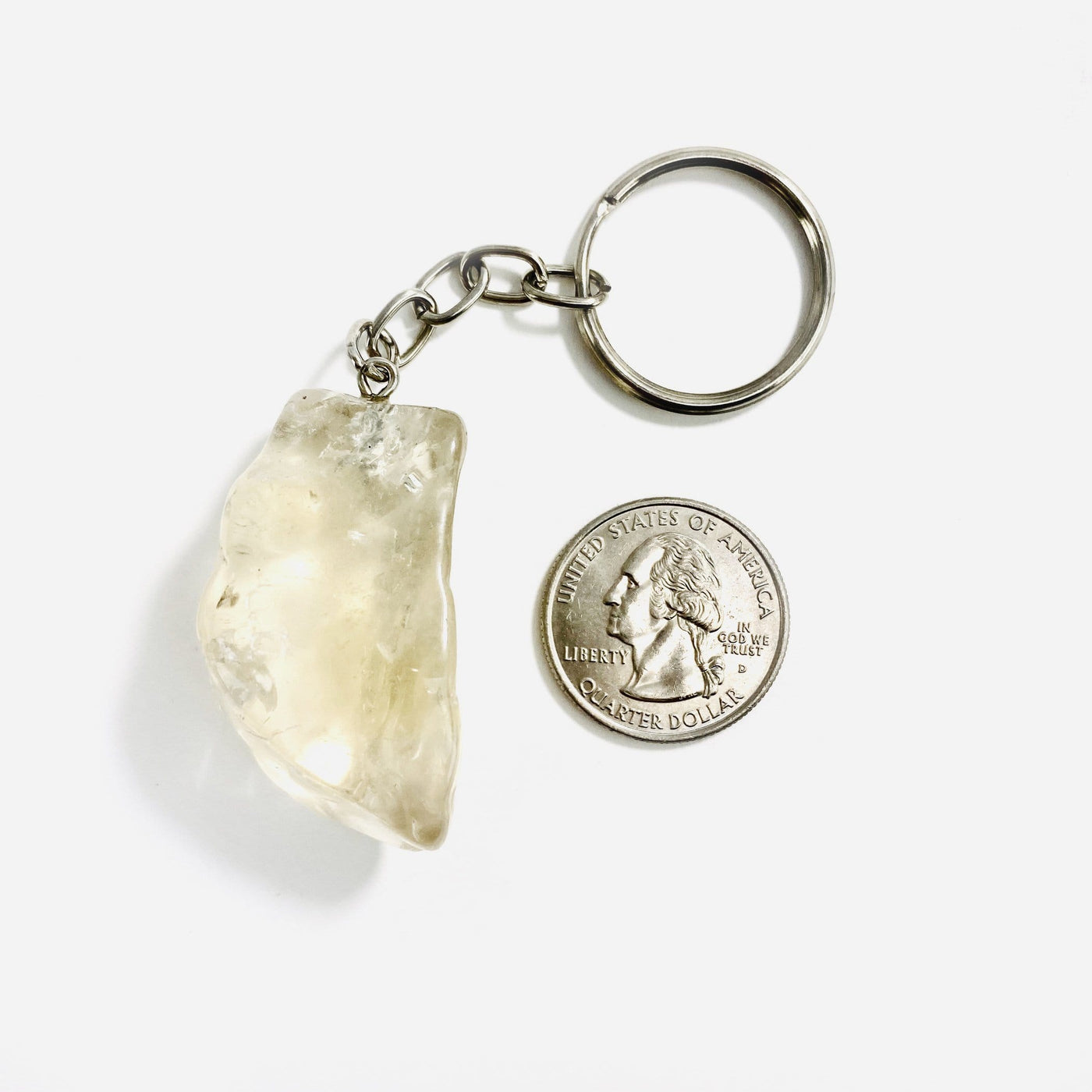 One citrine keychain on a white background next to a quarter showing the stone is a little bigger than the quarter.