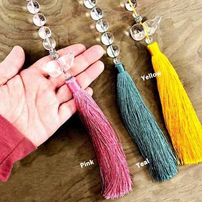 hand holding up pink Colored Tassels with Assorted Stone Bead next to teal and yellow