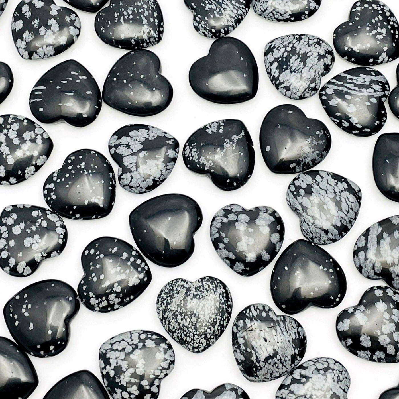 overhead view of many snowflake obsidian hearts filling up the white background for possible variations