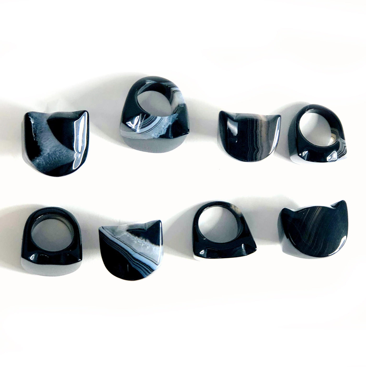 8 Black Agate Cat Polished Rings placed in 2 rows showing size and color difference