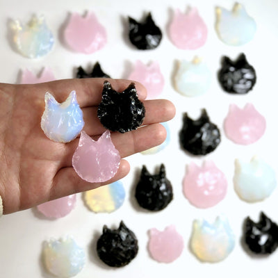 all 3 variations (opalite, rose quartz, and obsidian ) of cats in hand with more crystal cats in the background