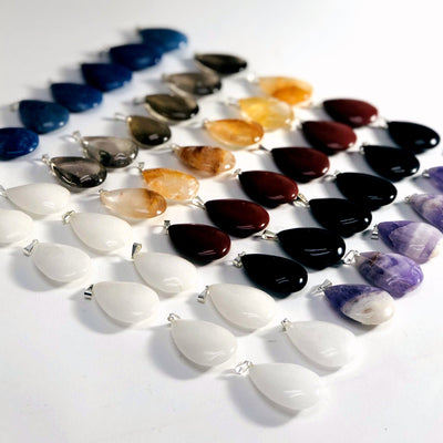 Gemstone Teardrop Pendants laid out on a table showing different shades of each stone available, this time from an angle