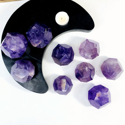 Amethyst Dodecahedron Stones --multiple dodecahedron for different sizes and shades on table.
