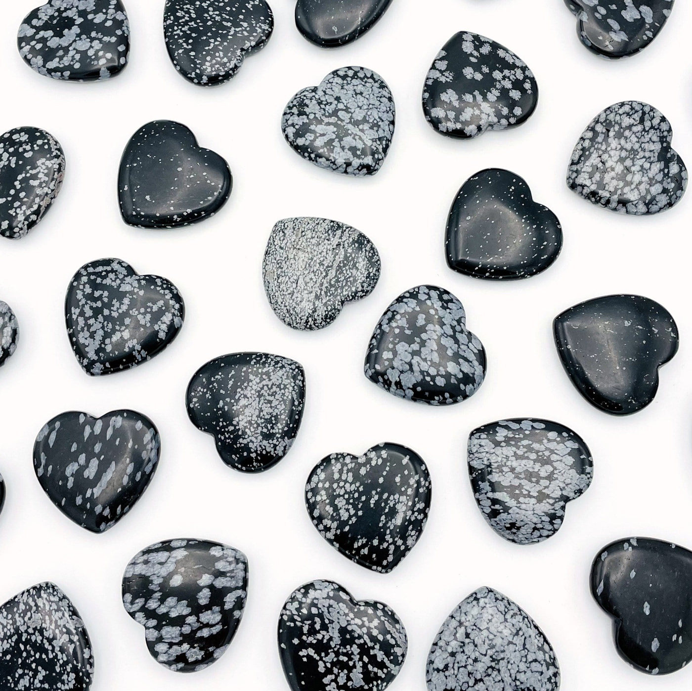 overhead view of many snowflake obsidian hearts on white background for possible variations