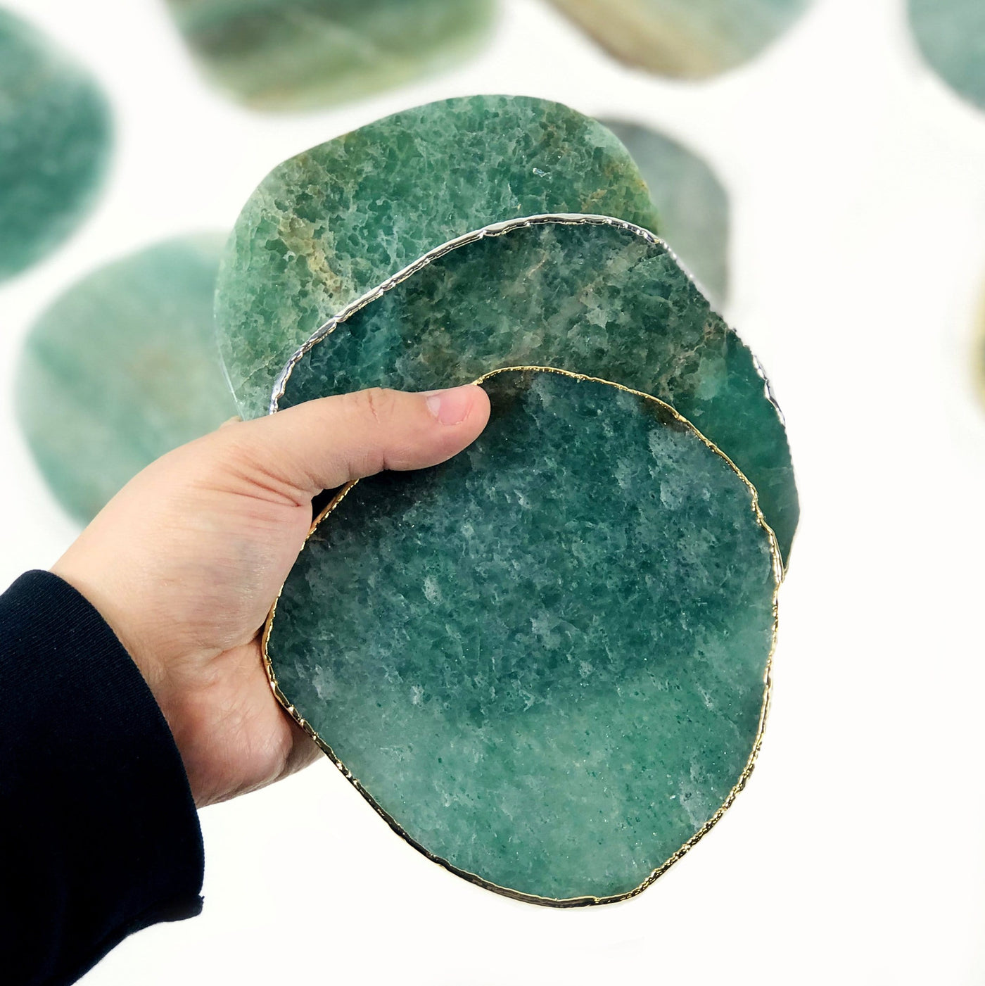green quartz coasters displayed in hand to show size reference and edges come in gold silver and raw edge