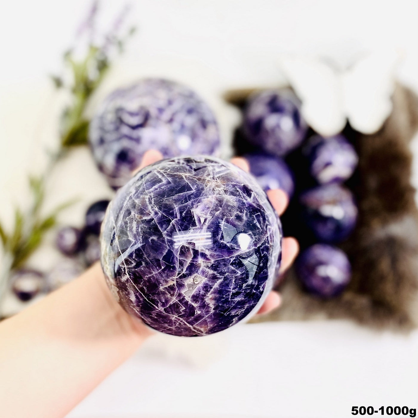 Chevron Amethyst Polished Spheres in a hand, size under 500g-100g