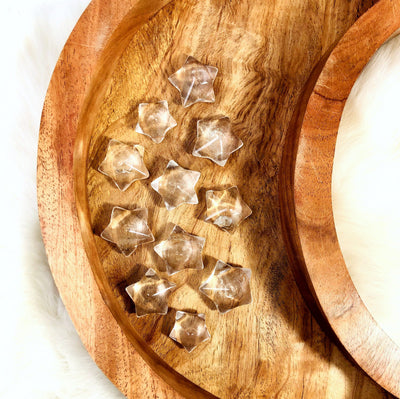 11 Crystal Quartz Puffy Star Cabochon Gemstones displayed on a wooden moon shaped tray.
