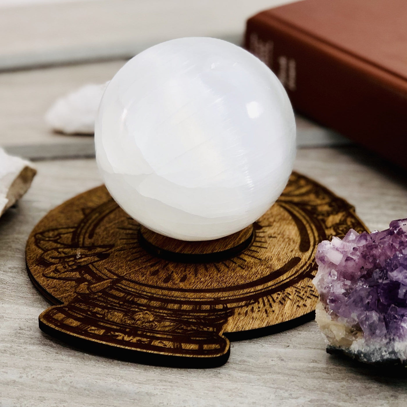 side view of psychichs crystal ball wooden sphere stand with selenite sphere in it