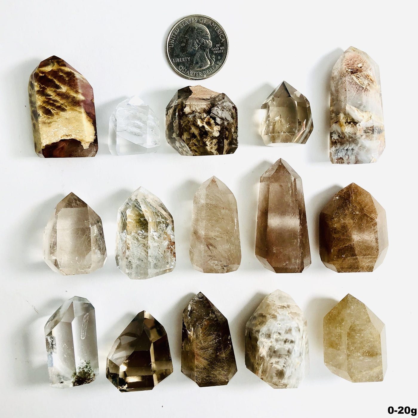 15 crystal points with inclusions next to a quarter for size reference on white background