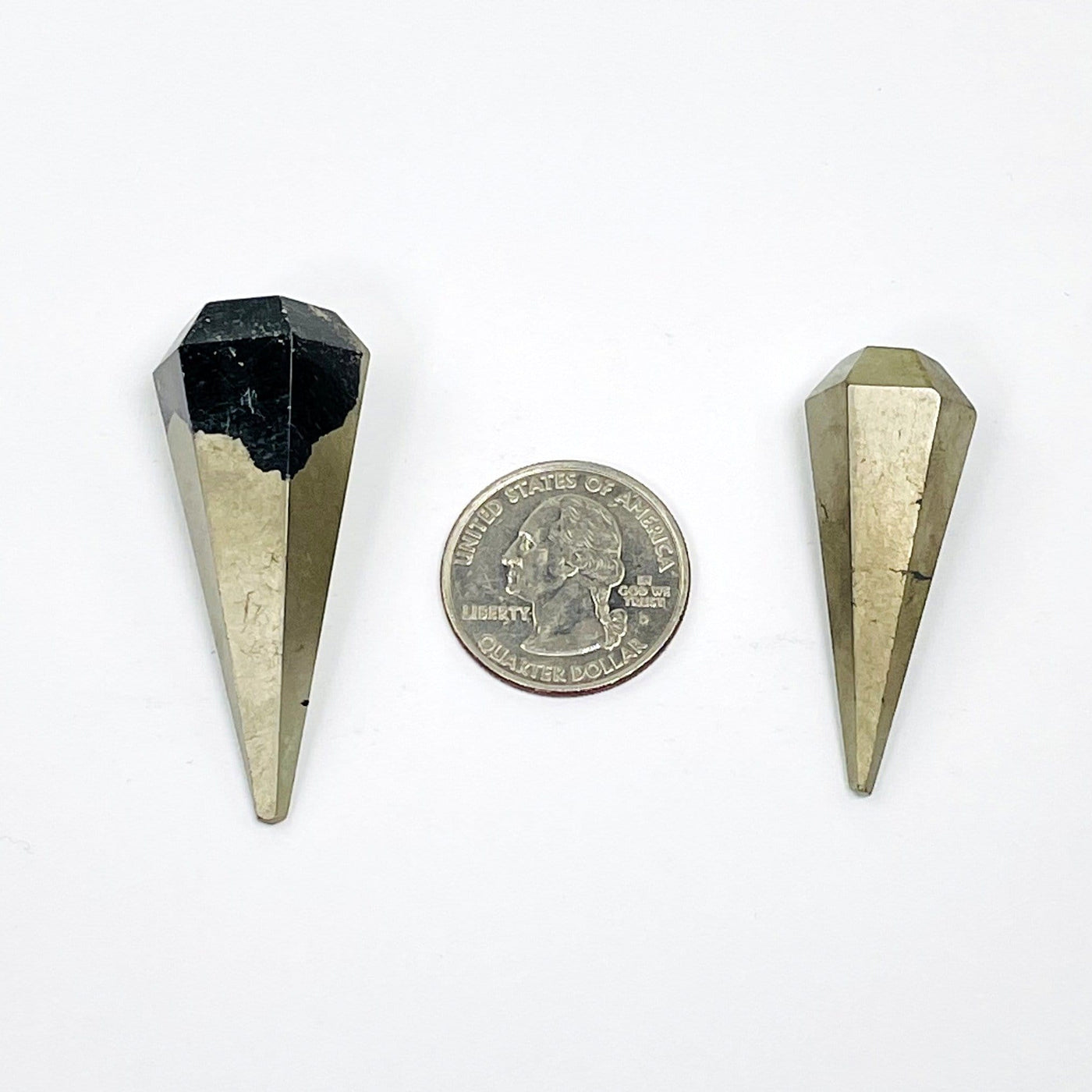 2 pyrite pendulum points next to a quarter for size reference 