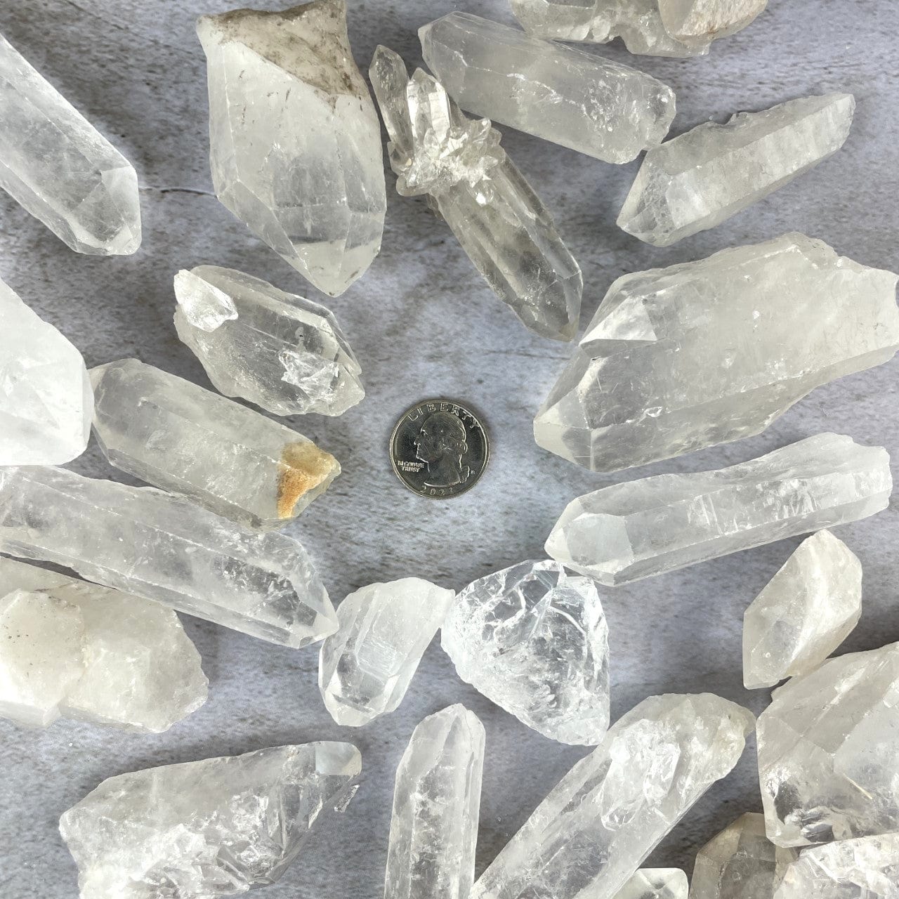 Crystal Quartz Points of assorted sizes around a quarter for size reference
