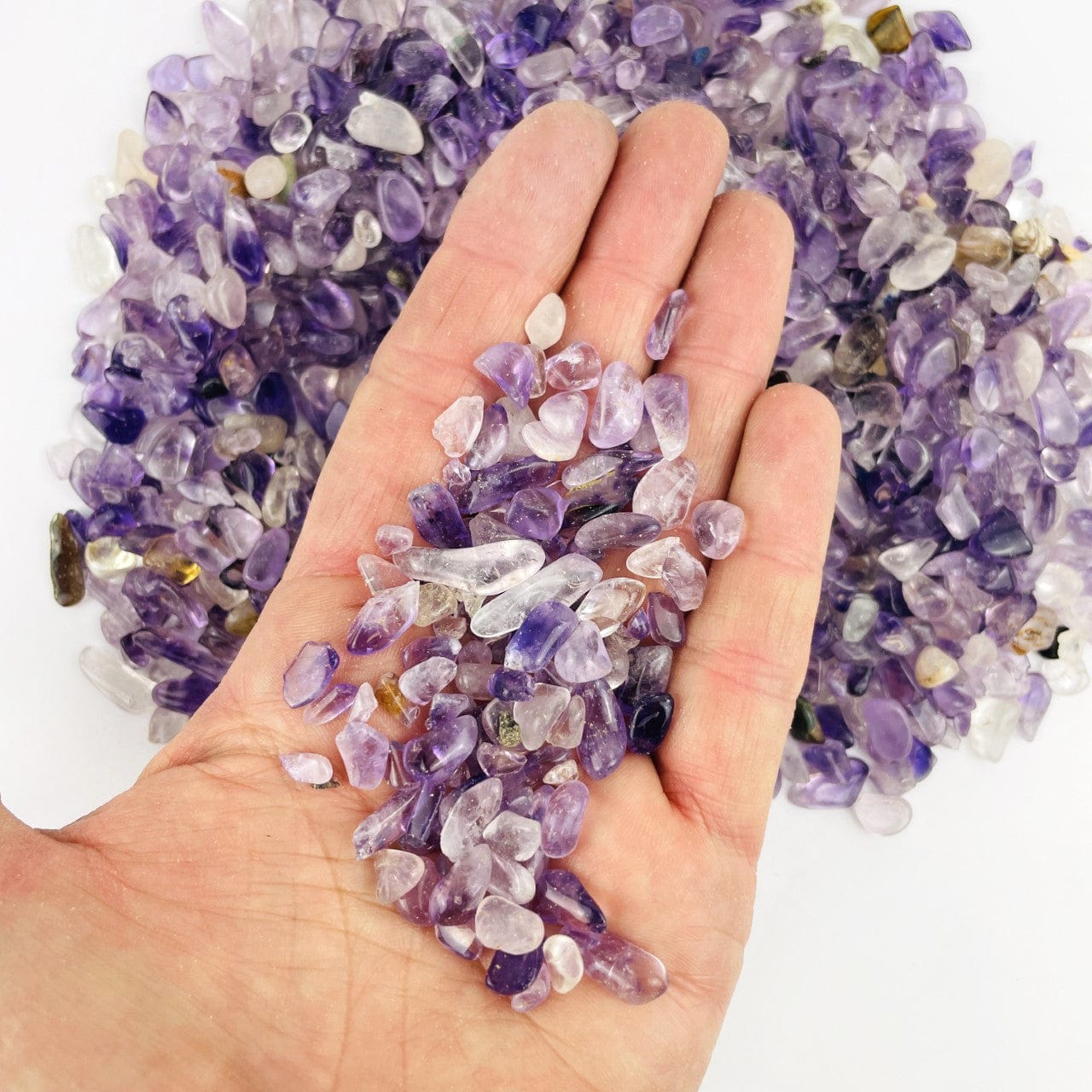  Amethyst Polished Small Chip Stones in a hand for size reference, with other stones behind