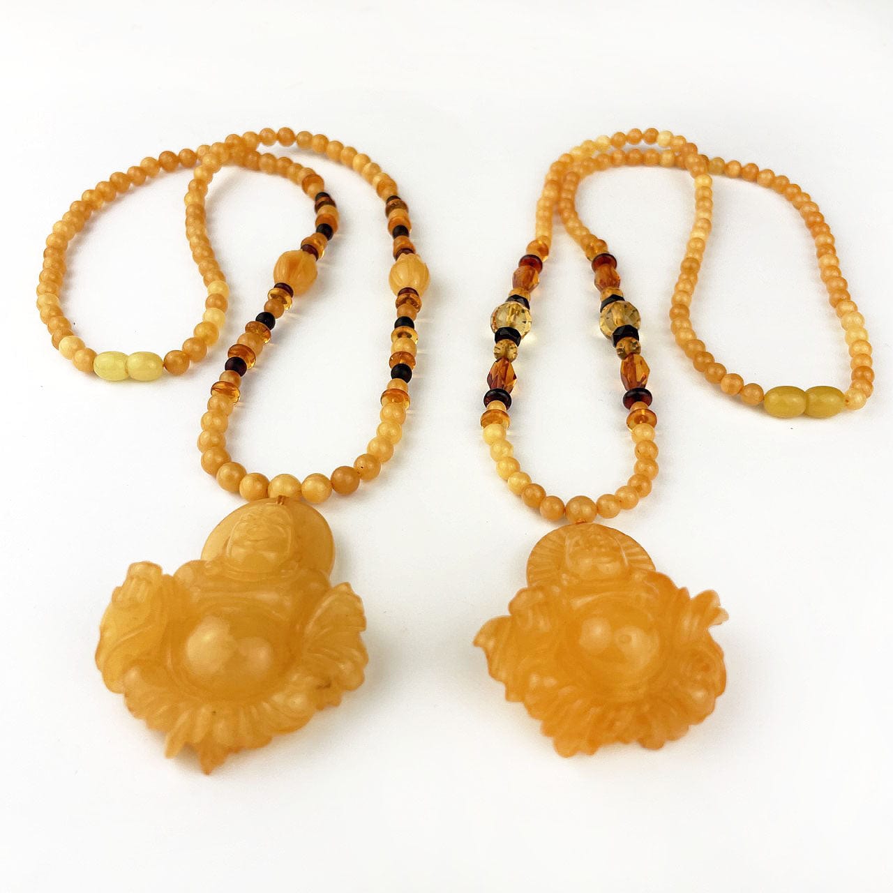 Amber Beaded Necklaces with Carved Buddha Pendants showing the carved buddhas at an angle so you can see the thickness