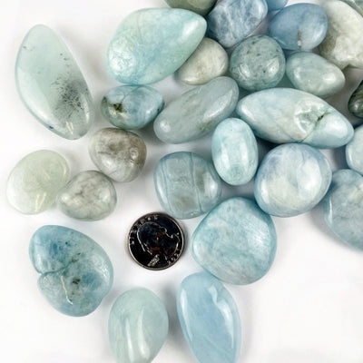 Aquamarine Tumbled Stones Nuggets surrounding a quarter for size reference