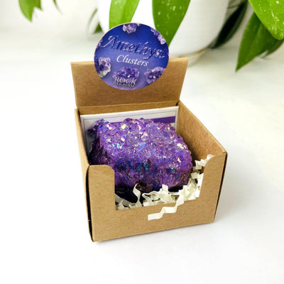 amethyst aura geode in box with decorations in the background