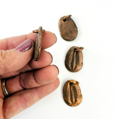 Copper Trilobites Pendants with 1 in a hand showing side view of the thickness