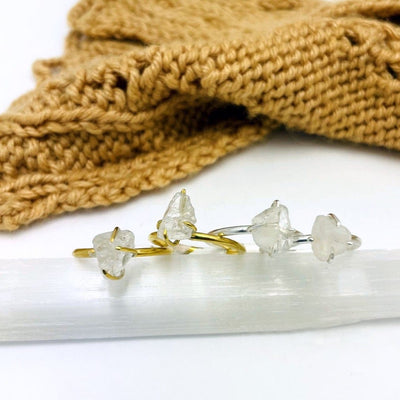 gold and silver rough stone gemstone rings shown on a selenite rod