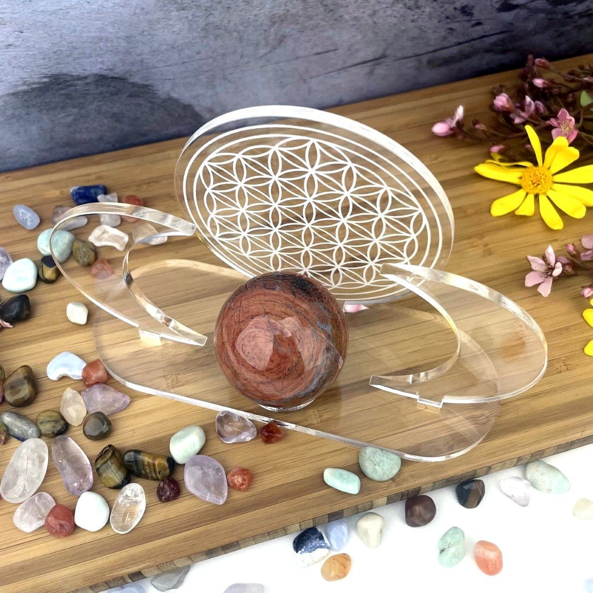 Acrylic Sphere Holder - Crescent Moons with Flower of Life shown from the top in an alter holding a sphere. Flowers and crystals surrounding the holder.