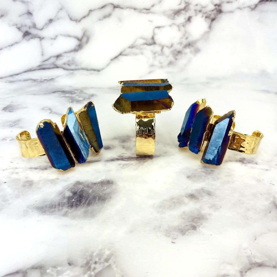 3 Titanium Crystal Quartz Triple Point Cuff Bracelet with Electroplated 24k Gold on marble background