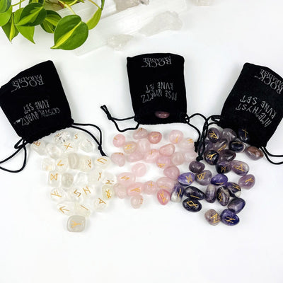 3 sets of Rune Alphabet Set of Stones spread out of a Velvet Bag, in the stones crystal quartz, rose quartz, and amethyst