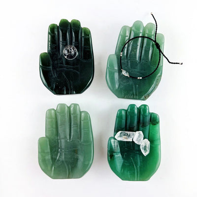 Hamsa Hand Stone Carvings in green aventurine, shown with crystals in one, a small sphere in one and a bracelet in one