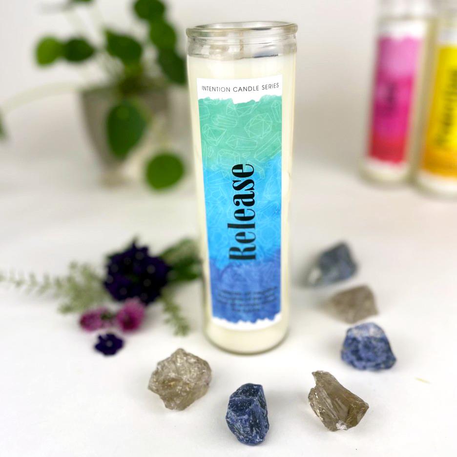 Release Intention Candle surrounded by crystals with plants and other candles blurred in the background
