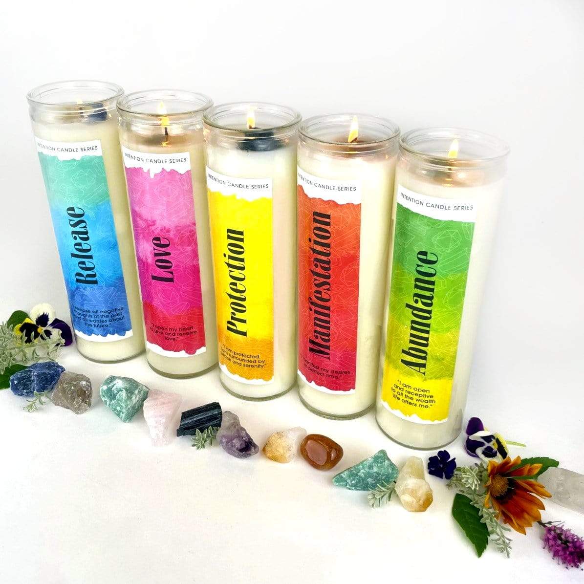 5 intention candles displayed with crystals and flowers.
