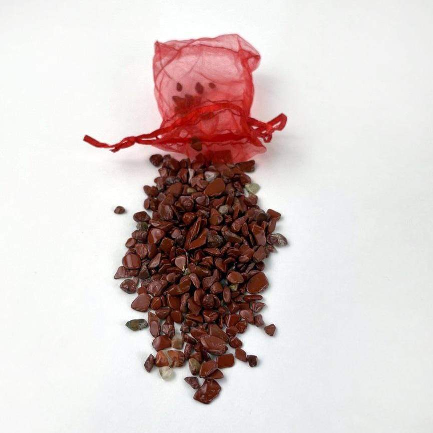 Red jasper chips spilled out of the bag with a red mesh bag.