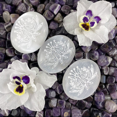 overhead view of selenite lotus engraved palm stones for engraving details and possible variations