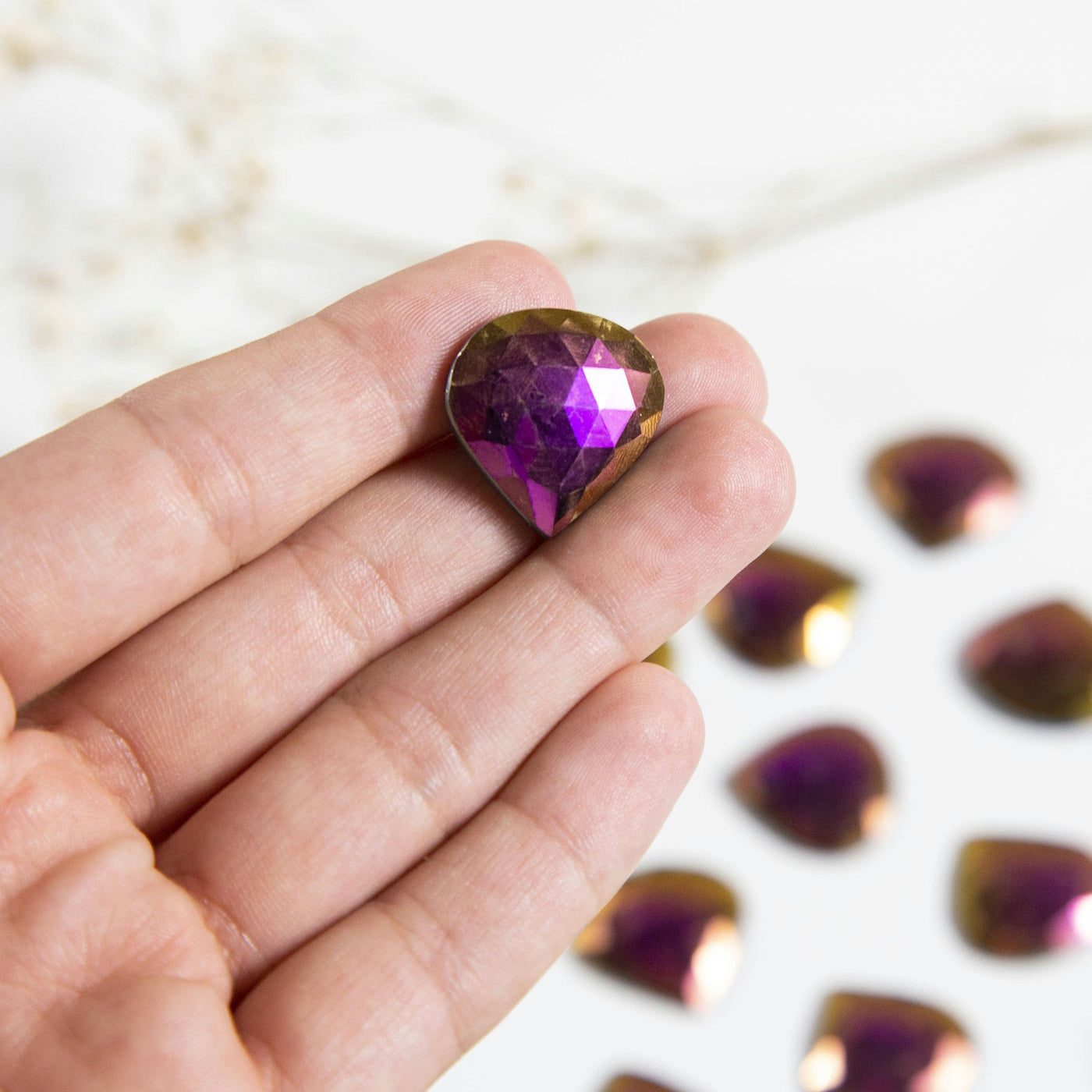hand holding up Titanium Teardrop Shaped Cabochon with others blurred in background