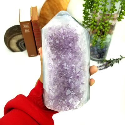 hand holding up Amethyst Geode Druzy Polished Cut Base with decorations in the background
