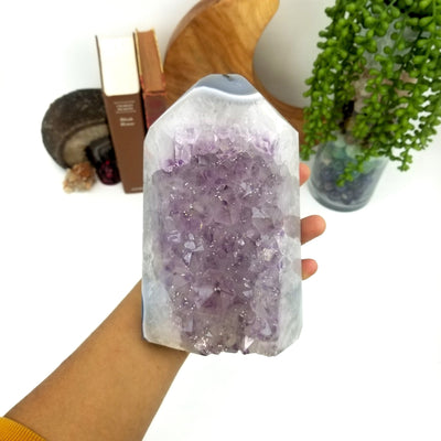 Amethyst cut base polished point held in a woman's hand.  It has a gray agate point, with light amethyst in the center, surrounded by crystal quartz on the edges.
