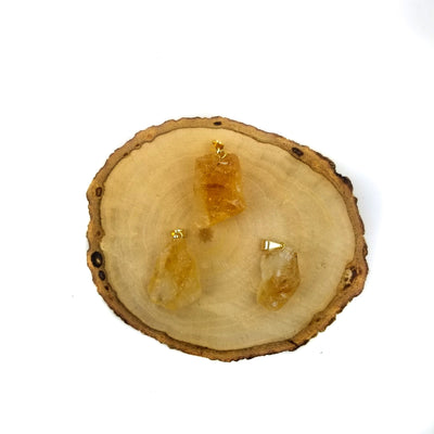 3 citrine pendants with gold bails on wooden coaster