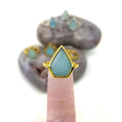 holding up Aqua Chalcedony Arrowhead Stone ring in gold with others in the background