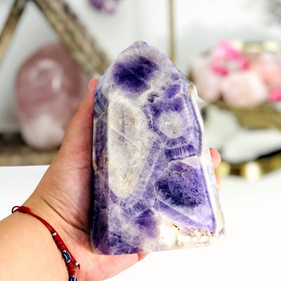 hand holding up Chevron Amethyst Polished Point with decorations blurred in the background