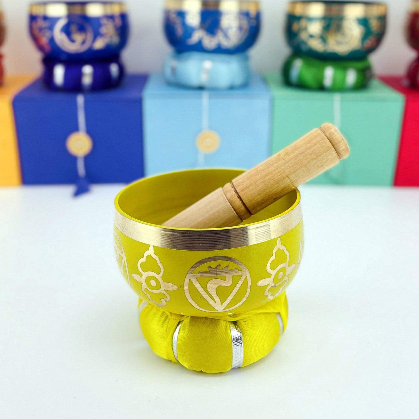 yellow Brass Tibetan Chakra Singing Bowl on top a pillow with a mallet inside
