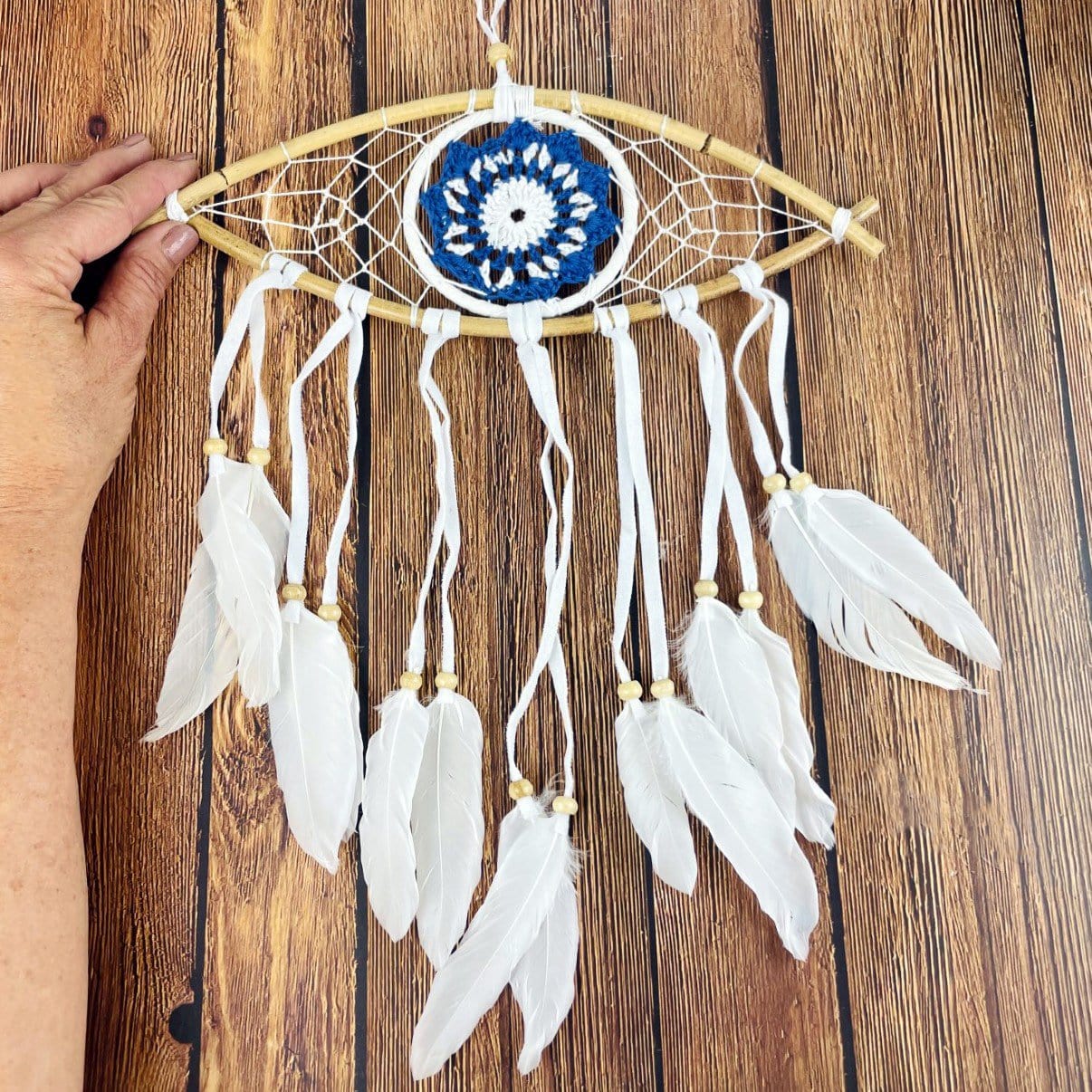 White Dream Catcher with  Blue All Seeing Eye Pattern  next to hand for size reference