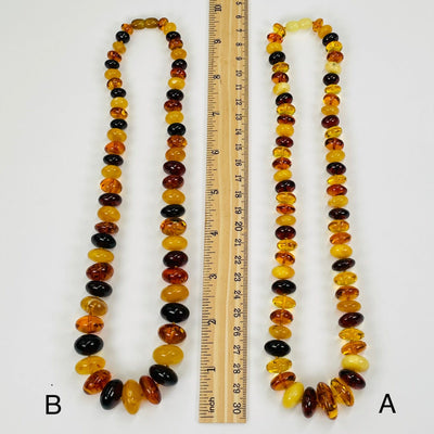 amber necklaces next to a ruler for size reference 