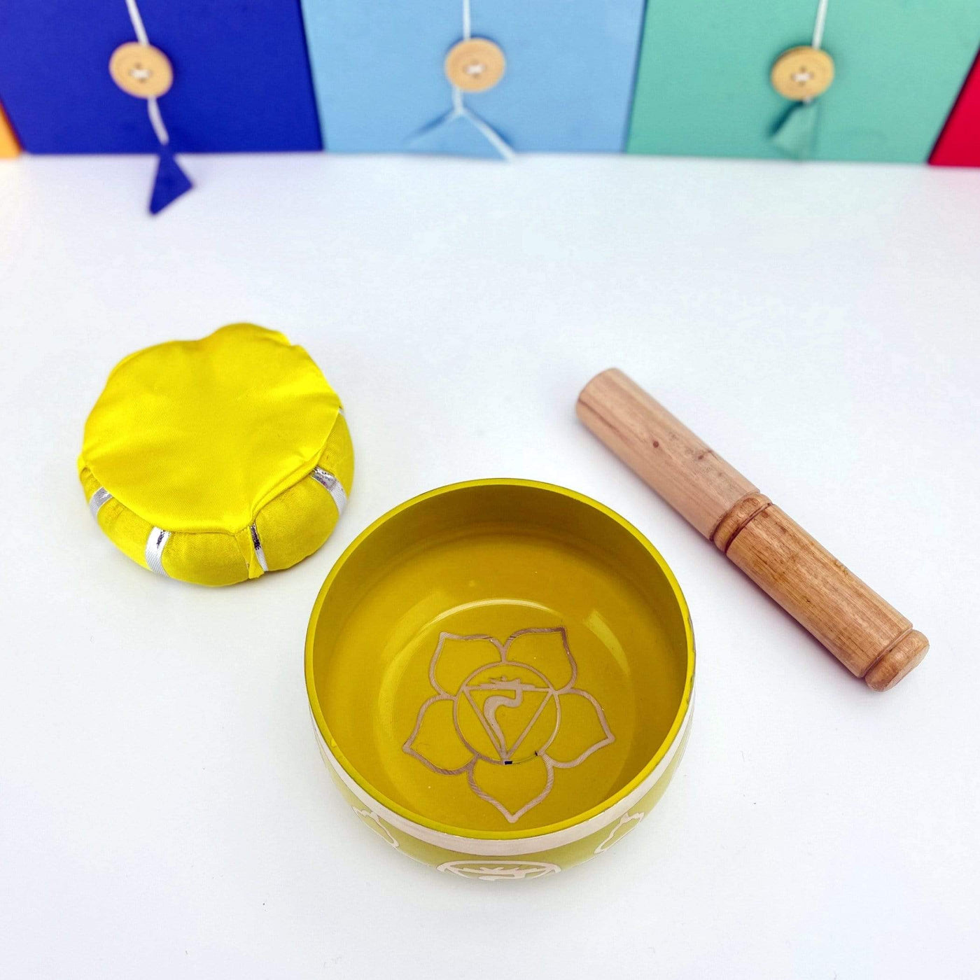 yellow Brass Tibetan Chakra Singing Bowl shot from above next to a pillow and a mallet