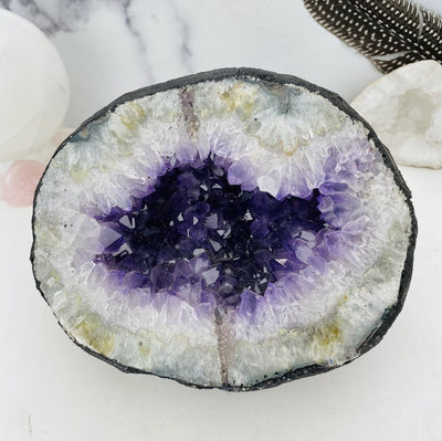 Amethyst geode.  It is round with a black outside, followed by crystal white and amethyst purple druzy in the center.