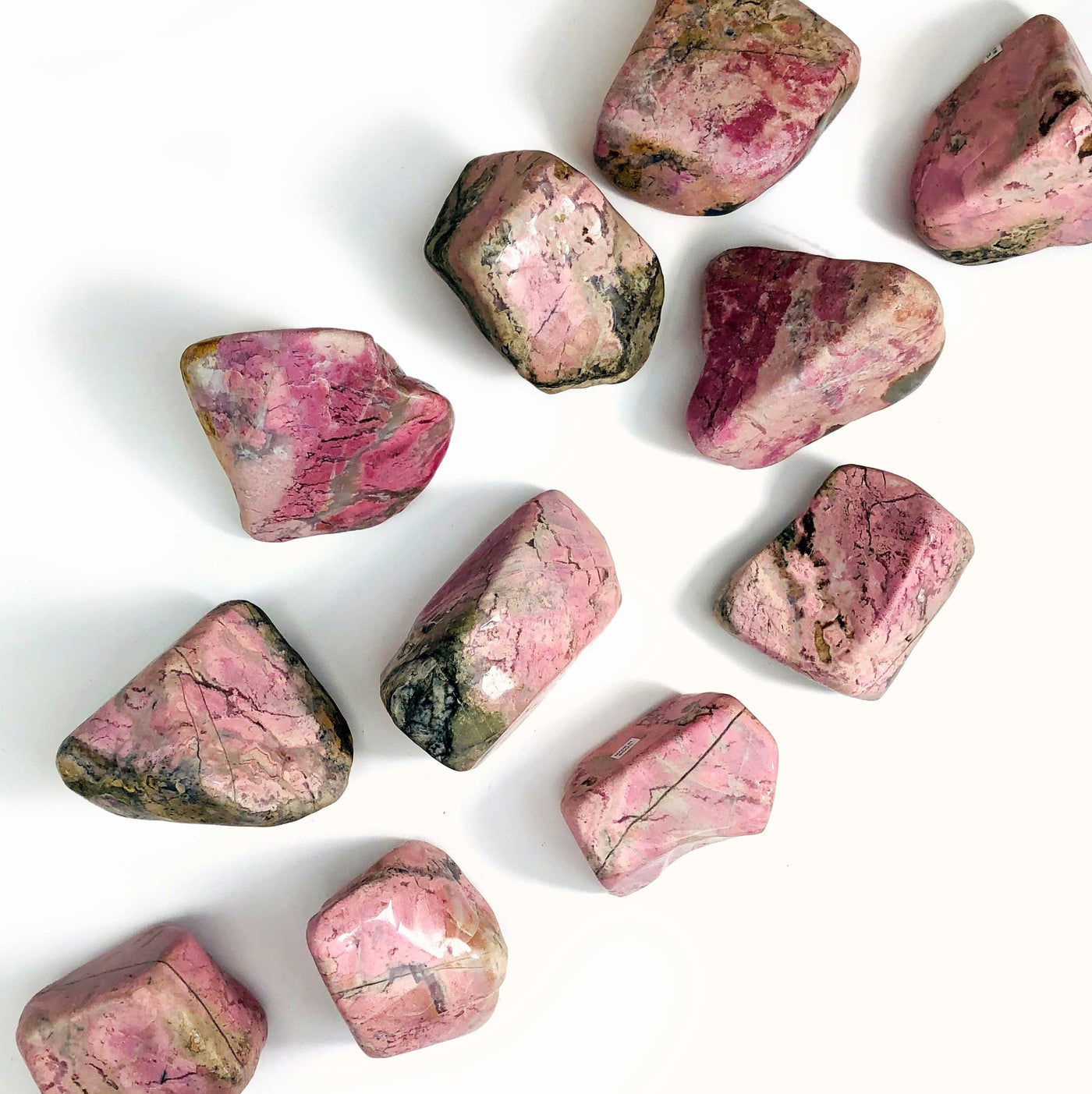 Rhodonite Tumbled Polished Stones scattered on white background