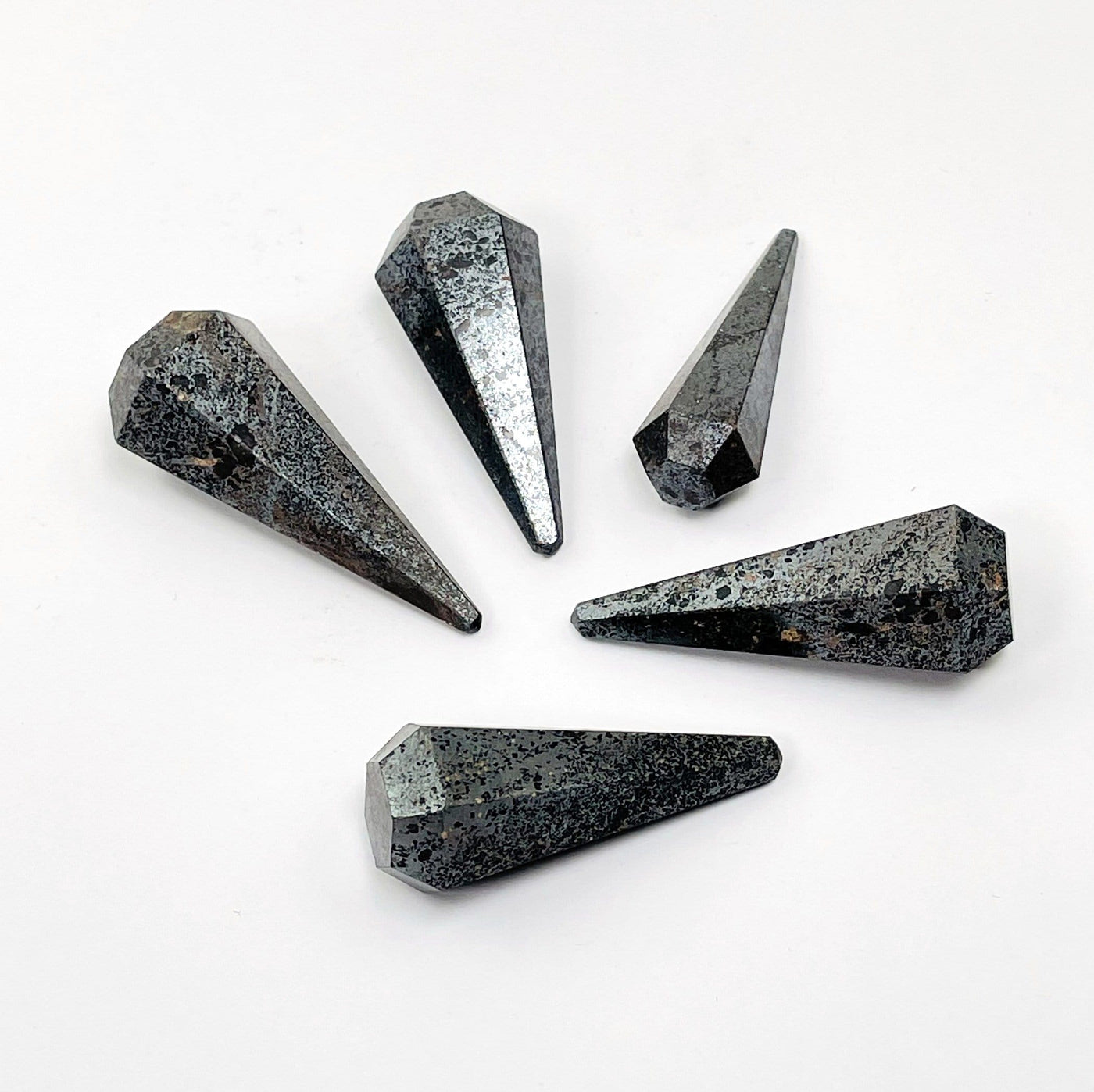 multiple hematite pendulum points placed around each other to show size and design differences