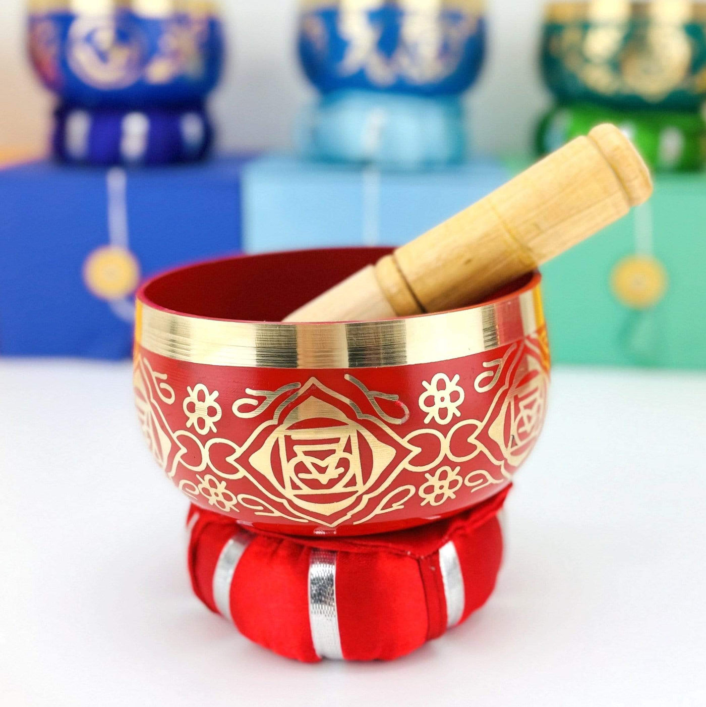 red Brass Tibetan Root Chakra Singing Bowl on a pillow with a mallet inside