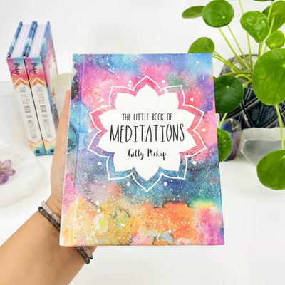 Hand holding The Little Book of Meditations by Gilly Pickup