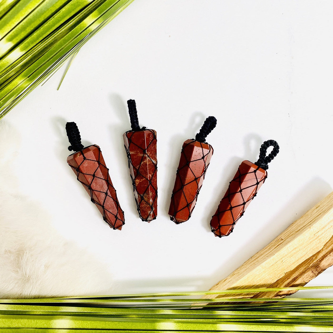 4 Red Jasper Points - Netted Pendants black variant with dried plants on white background
