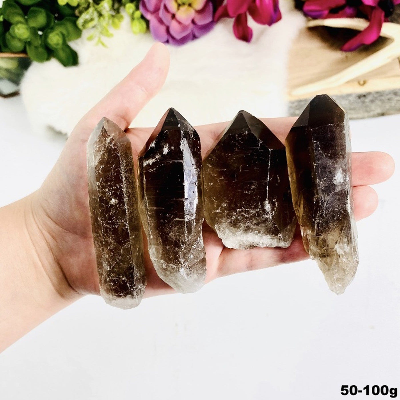 four 50g - 100g smokey quartz raw point rods in hand for size reference and possible variations