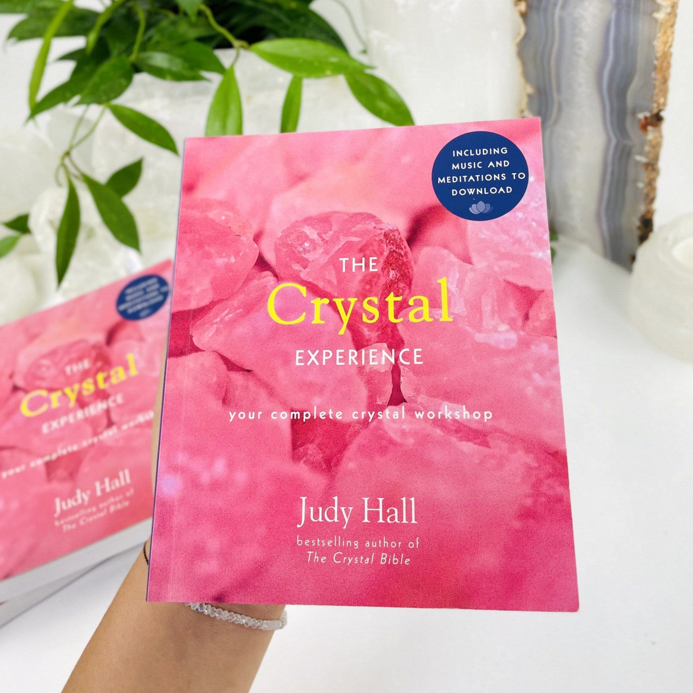 Hand holding A book called The Crystal Experience by Judy Hall