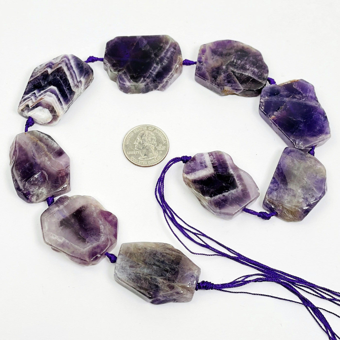 Chevron Amethyst slab beads - Polished Beads--quarter used for size comparison next to stones on table.