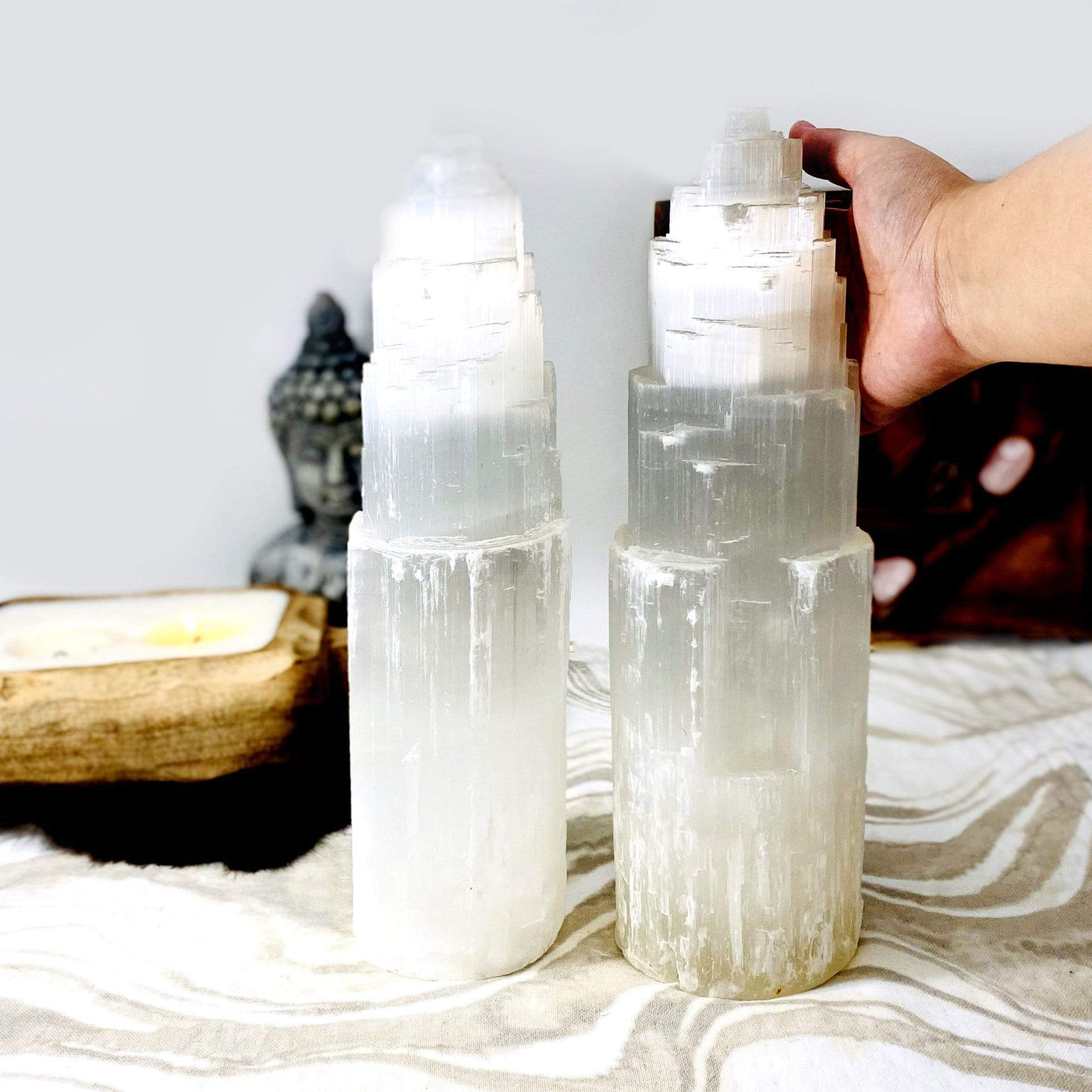 two selenite lamps side by side with a hand next to the one on the right.