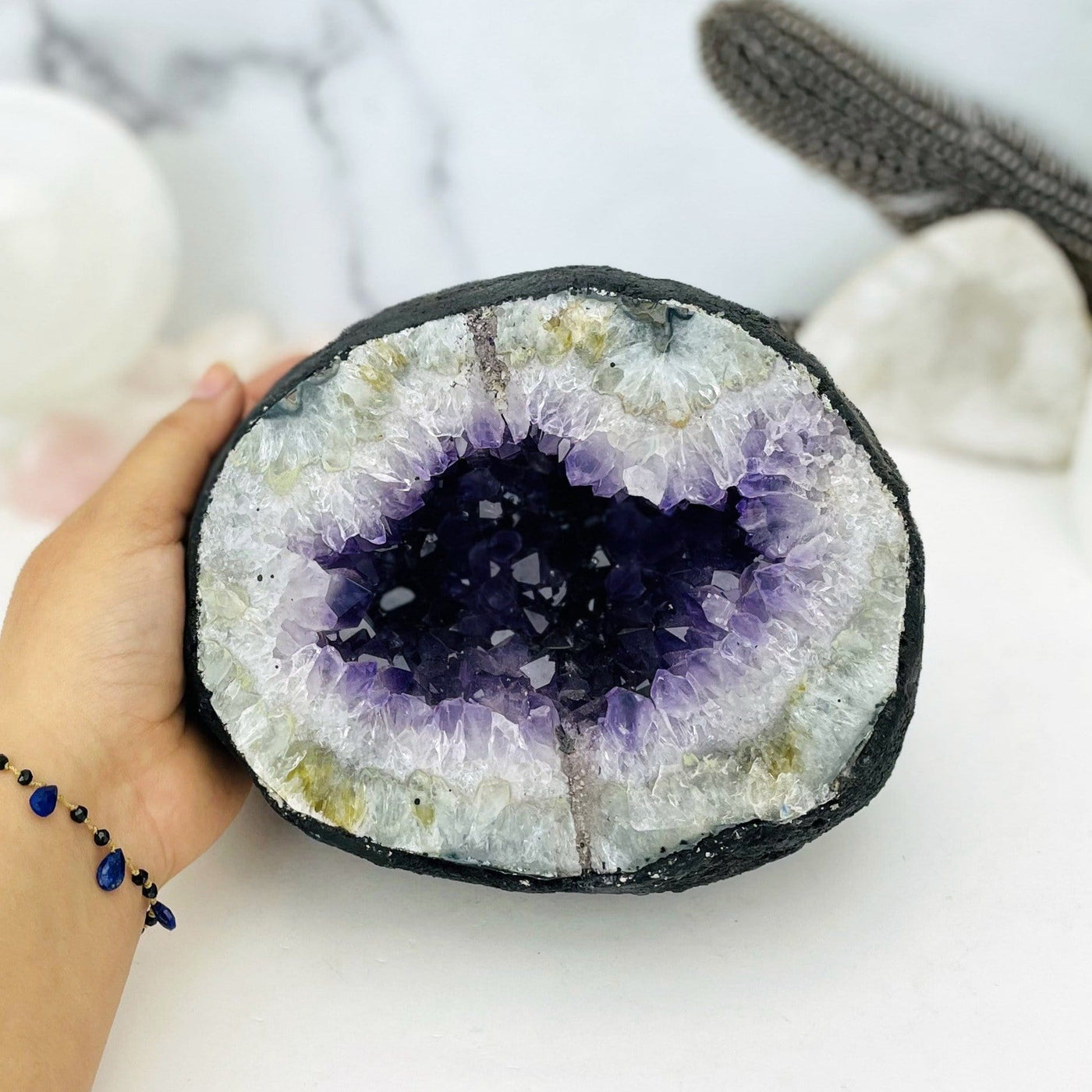 Amethyst geode.  It is round with a black outside, followed by crystal white and amethyst purple druzy in the center.  